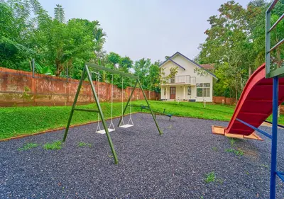 a group of swings in a yard with a house at Kedara Resort Wayanad by VOYE HOMES - Pet Friendly with Pool in Sultan Bathery