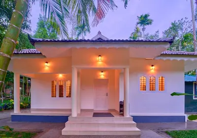 a white house with a front entrance with palm trees at Kedara Resort Wayanad by VOYE HOMES - Pet Friendly with Pool in Sultan Bathery
