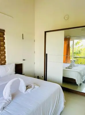 a bedroom with a white bed with a large mirror at Zero Degree in Ketti