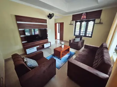 a living room with two couches and a flat screen tv at Tranquil Nest Villa - Wayanad in Kalpetta