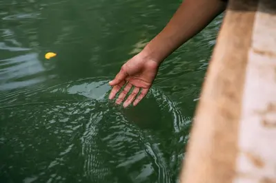 a person holding their hand in the water at Ganesha Homestay, Cochin, Near Paniyeli Poru Waterfalls in Malayāttūr