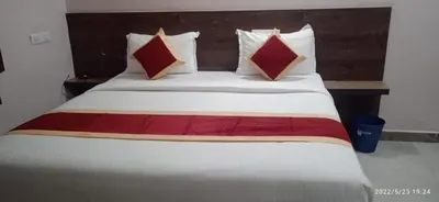 a bed with red and white pillows in a room at Parvathi comforts inn in Mysore