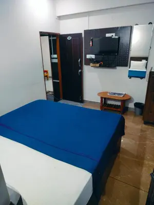 a bedroom with a bed and a tv and a table at Parvathi comforts inn in Mysore