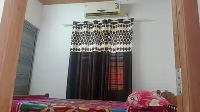 a bedroom with a black curtain and a window at Suraj Stays Glowing Meadows in Chewarra