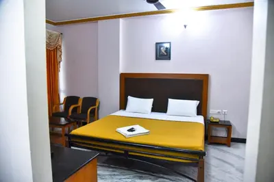 a room with a bed and two chairs in it at Hotel Grand Palace in Coimbatore