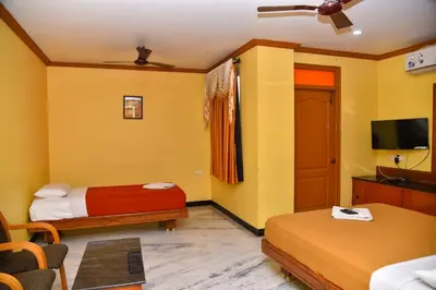 a hotel room with two beds and a flat screen tv at Hotel Grand Palace in Coimbatore