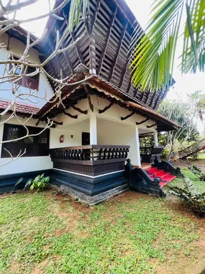a house with a thatched roof and a yard at Tapovan Green County Resorts in Thattakād