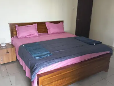 a large bed with pink pillows and a wooden headboard at City Nature-view apartment in Kozhikode