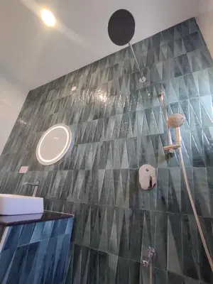 a bathroom with a tiled wall and a sink at 3BHK - Villa - a greece style - Kayal vizha - near isha yoga - coimbatore in Coimbatore