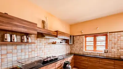 a kitchen with brown and white tiled walls and a window at Willostays Cluster Clouds in Ooty