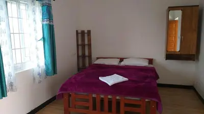 a bedroom with a bed with a purple blanket at diamond hill view cottage in Ooty