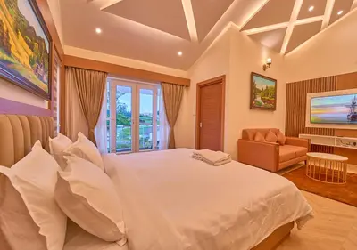a bedroom with a large white bed and a couch at Villa Terra Verde Ooty by VOYE HOMES in Ooty