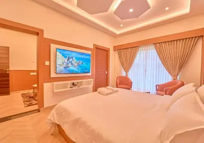 a bedroom with a large bed and a flat screen tv at Villa Terra Verde Ooty by VOYE HOMES in Ooty
