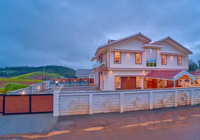 a large house with a fence on top of it at Villa Terra Verde Ooty by VOYE HOMES in Ooty