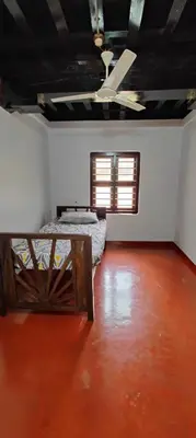 an empty room with two beds and a window at Traditional Kerala house, Kannur-Thalassery in Tellicherry