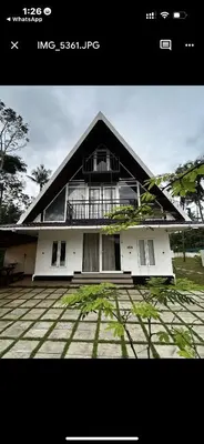 a white house with a black roof at Paradise-Vadanappally Beach Villa for 4-5 adults in Irimbranallūr