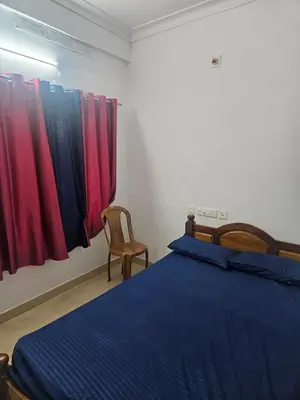 a bedroom with a bed and a chair and curtains at grandresidency in Kāladi