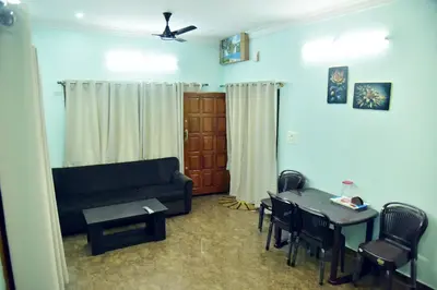 a living room with a couch and a table and chairs at Mysuru Family Home Stay in Mysore