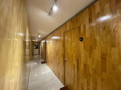 a hallway with wood paneled walls and a door at The Marina Kozhikode AC Rooms and Dorms Opposite to Beach in Kozhikode