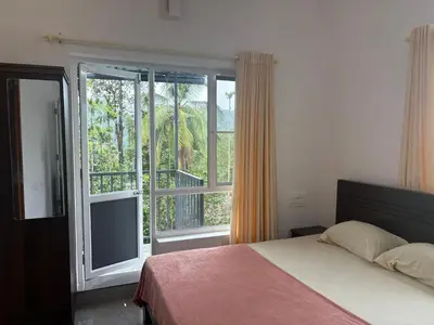 a bedroom with a bed and a large window at Eve's Residency in Meppādi