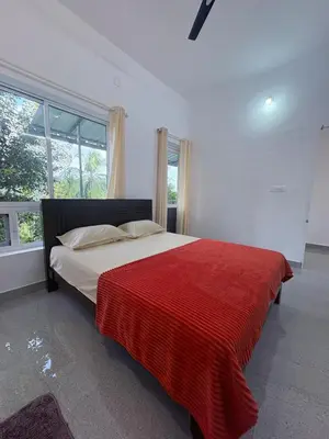 a bedroom with a large bed with a red blanket at Eve's Residency in Meppādi