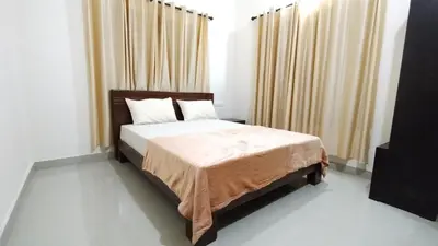 a bedroom with a large bed with curtains at Eve's Residency in Meppādi