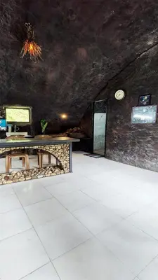 a room with a table and a stone wall at Mamalakandam Rock Cave at Diya Homestay in Mamalakandam