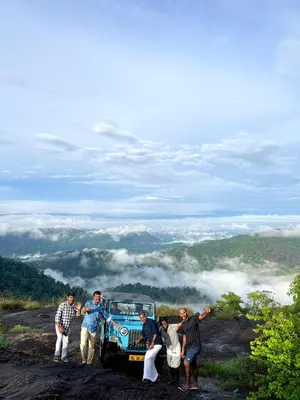 a group of people standing around a blue car on a hill at Mamalakandam Green Hill Stay in Diya Homesay in Mamalakandam