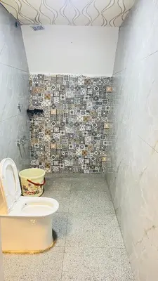 a bathroom with a toilet and a tiled wall at Airas Resort in Kūkkāl
