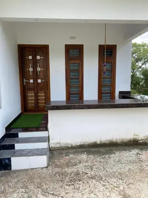 a white building with wooden doors and stairs at Travango Settukunnu in Vythiri