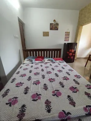 a bed with a bedspread with flowers on it at Guruvayur Soorya Madhavam Apartment B10, Shruthi, close to Temple, only150 Mtrs to North Nada in Guruvāyūr