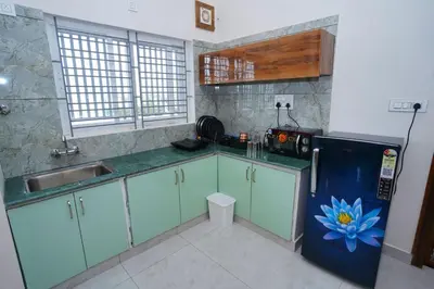 a kitchen with green cabinets and a blue refrigerator at Samruddhi Service Apartments in Mysore