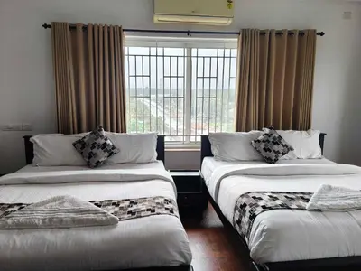 two beds in a room with a window at Townhouse Kozhikode Beach Formerly Point Avenue in Kozhikode