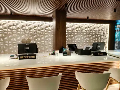 a restaurant with a reception counter with white chairs at Townhouse Kozhikode Beach Formerly Point Avenue in Kozhikode