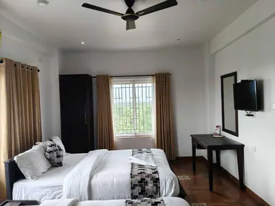 a bedroom with a bed and a ceiling fan at Townhouse Kozhikode Beach Formerly Point Avenue in Kozhikode