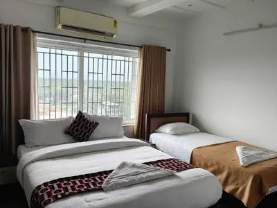 two beds in a room with a window at Townhouse Kozhikode Beach Formerly Point Avenue in Kozhikode
