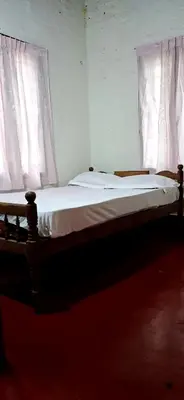 a bed in a room with two windows at Pookie stay athirapilly in Athirappilly