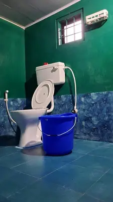 a toilet in a green room with a bucket at Pookie stay athirapilly in Athirappilly