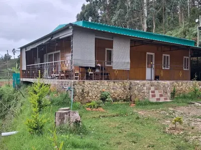 a house with a green roof and a stone wall at Kookal Candle Wood House in Kūkkāl