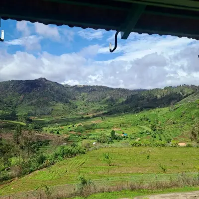 a view of a green field with mountains in the background at Kookal Candle Wood House in Kūkkāl