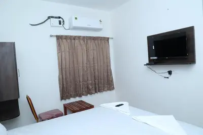 a room with a table and a tv and a window at Hotel Aranmanai in Coimbatore