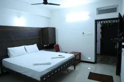 a bedroom with a large bed with white sheets at Hotel Aranmanai in Coimbatore