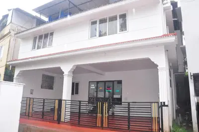 a white house with a gate in front of it at HS Cottage Ooty in Ooty