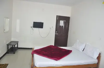 a room with a bed and a tv on the wall at HS Cottage Ooty in Ooty
