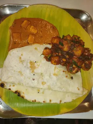 a green plate of food with meat and sauce at Hanni Resort in Kotagiri