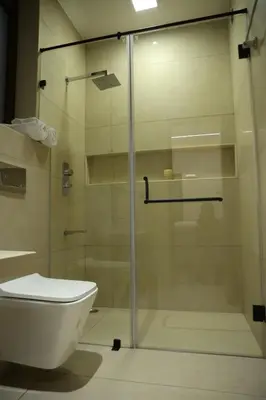 a bathroom with a glass shower with a toilet at Hills and Hearts Luxury Villa in Coonoor