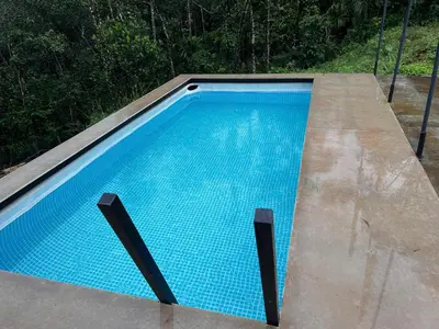 an empty swimming pool with blue water on a patio at Bambus Alley in Wayanad
