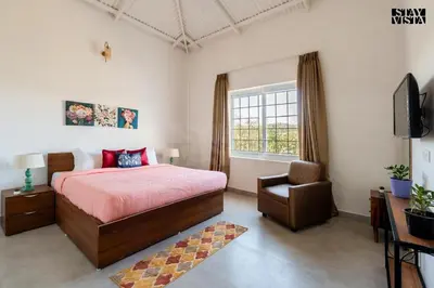 a bedroom with a bed and a chair and a television at The Lake House Ooty in Ooty