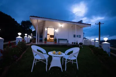 two chairs and a table in a yard at night at The Lake House Ooty in Ooty