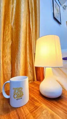 a table with a coffee cup and a lamp on it at TS Club in Trichūr